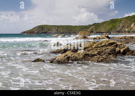 Sea and rocks with cliffs in the background at Kennack Sands, The Lizard Peninsula, Cornwall, UK Stock Photo