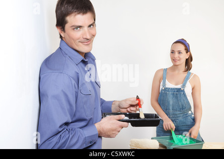Portrait of young husband mixing paint while wife watching Stock Photo