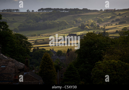 Early morning sun breaking through clouds on the hills above Oxenhope. Stock Photo