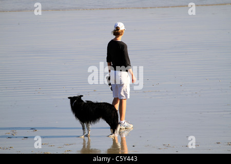Woman exercising her Border Collie on the beach at Milnerton near Cape Town. Stock Photo