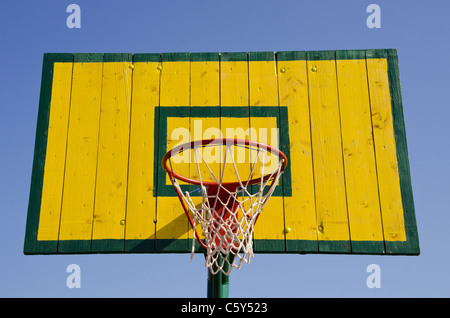 Basketball board painted green and yellow with net on the hoop. Stock Photo