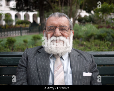 Hispanic businessman with beard sitting on a park bench. Stock Photo