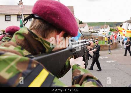 Youth dressed as a British Soldier from the Parachute Regiment points a rifle at a group of Republican marchers Stock Photo