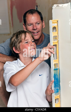 Father and son check level with tool as they remodel kitchen. MR © Myrleen Pearson Stock Photo
