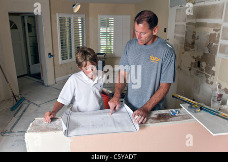 Father and son read blueprint as they DIY remodel kitchen. MR © Myrleen Pearson Stock Photo