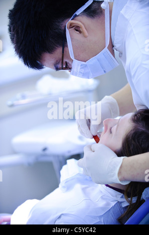 Dentist performing dental surgery and tooth molding on patient in dental clinical setting Stock Photo