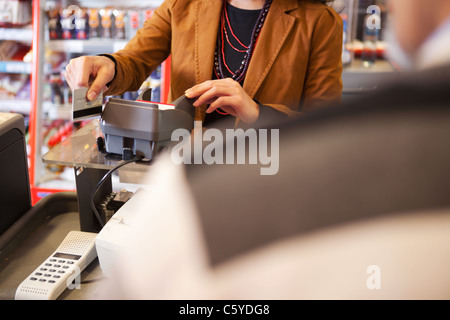 Shop assistant swiping credit card in supermarket with customer in the foreground Stock Photo