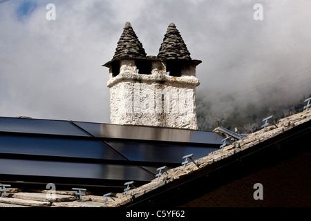 Chimney stacks on a roof covered with cut slates (Cogne - Italy). Souches de cheminées sur un toit de lauzes taillées (Italie). Stock Photo