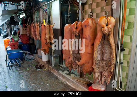 Barbecued Cured Pig Carcasses Hanging in an Alleyway next to a Butchers Shop near Tung Choi Street in Kowloon Stock Photo