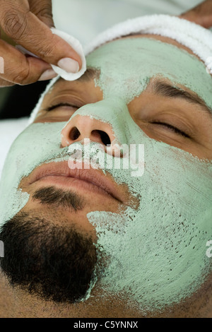 USA, California, Oakland, beautician removing facial mask from man's face in spa Stock Photo