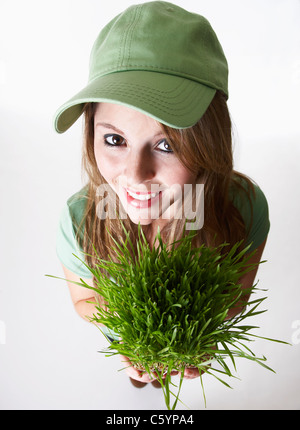 USA California, Fairfax, studio portrait of smiling young woman holding wheat grass Stock Photo