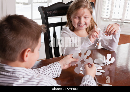 USA, Illinois, Metamora, brother (8-9) and sister (6-7) making paper cutouts Stock Photo