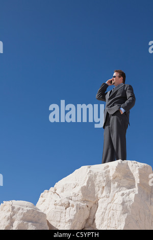 USA, New Mexico, Whitesands, Businessman at the edge of rock talking via phone Stock Photo