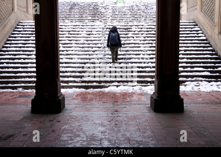 A lone girl walks through the Bethesda Terrace arcade in the snow in the New York winter Stock Photo