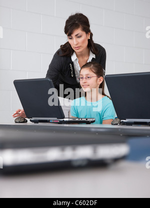 Girl (6-7) with female teacher using laptop in classroom Stock Photo ...
