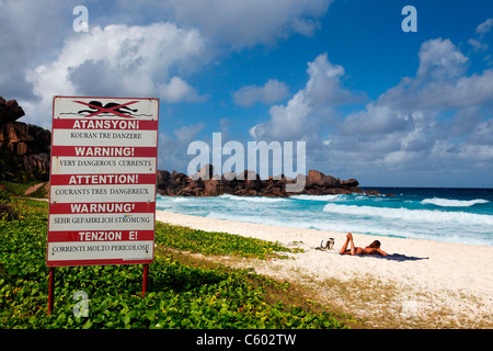 Women sunbathing at wild Grand Anse beach with strong currents on East Coast, La Digue, Seychelles, Indian Ocean, Africa Stock Photo