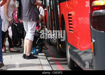 people getting off a red London double decker bus at a bus stop - one lady with a puschair Stock Photo