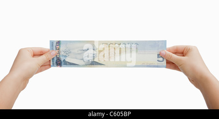 USA, Illinois, Metamora, Studio shot of woman's hands stretching Canadian five-dollar bill Stock Photo