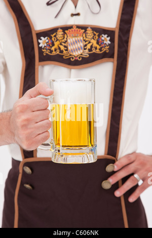 Man wearing Oktoberfest costume holding mug of beer Stock Photo