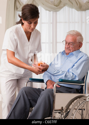 USA, Illinois, Metamora, Female nurse giving pills to senior man on wheelchair Stock Photo
