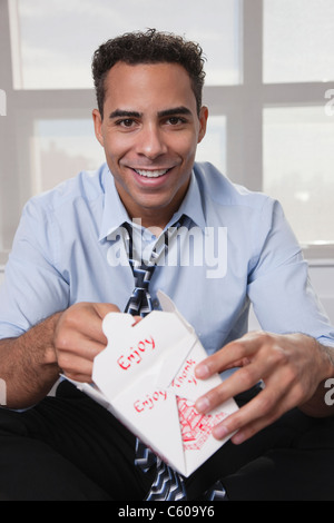 USA, New York, New York City, portrait of smiling young man eating Chinise food Stock Photo