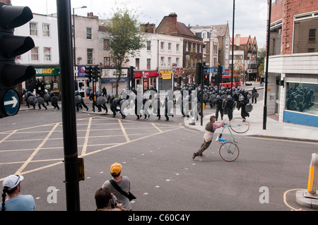 Man with a bicycle getting out of the way of riot police running down Mare Street, London Riots - Hackney Central - 8/8/2011 Stock Photo