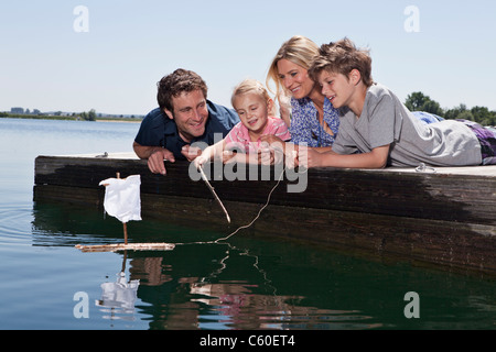 Couple playing with toy boat on dock Stock Photo