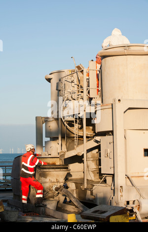 Workers mixing grout on a jack up barge to cement wind turbine pieces into place, Walney offshore wind farm. Stock Photo