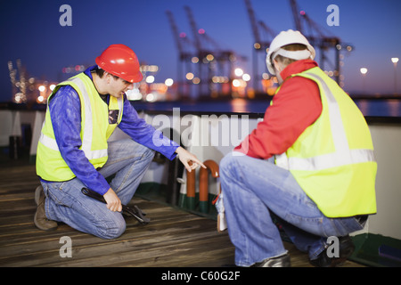 Workers examining machinery on ship Stock Photo