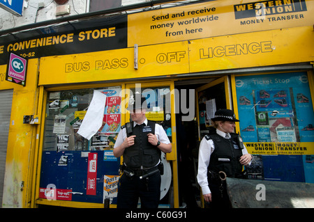 Clarence Road, scene of last night's riot. Convenience store trashed in last night's riot guarded by police Stock Photo