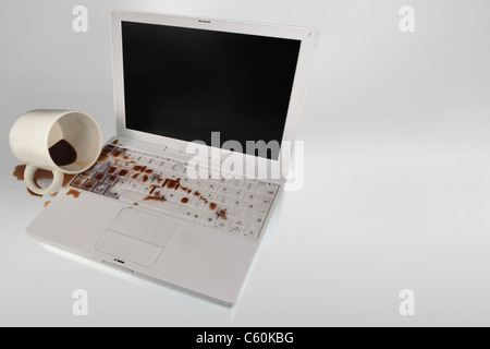 A cup of coffee accidentally spills on the keyboard of the laptop computer. Copy-space. Stock Photo