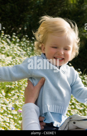 Parent holding baby in field of flowers Stock Photo