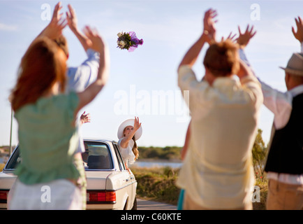 Bride throwing bouquet from car Stock Photo