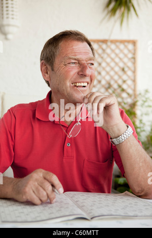 Older man completing crossword puzzle Stock Photo