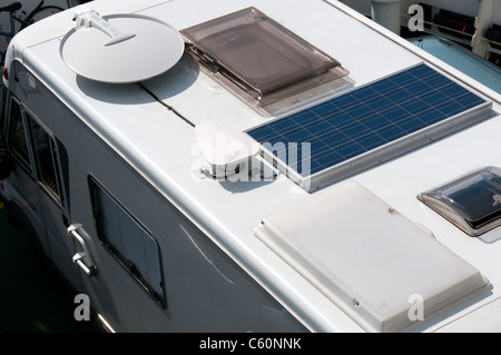 Satellite dish and PV solar cell or panel on the roof of a camper van. Stock Photo