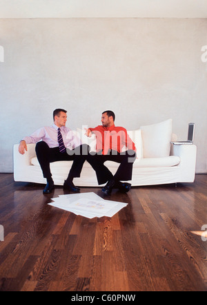 Businessmen talking on couch in office Stock Photo
