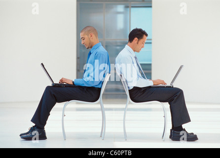 Businessmen using laptops in lobby Stock Photo