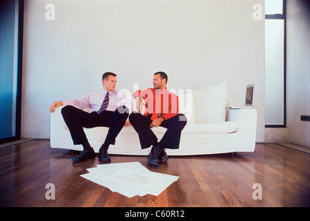 Businessmen talking on couch in office Stock Photo