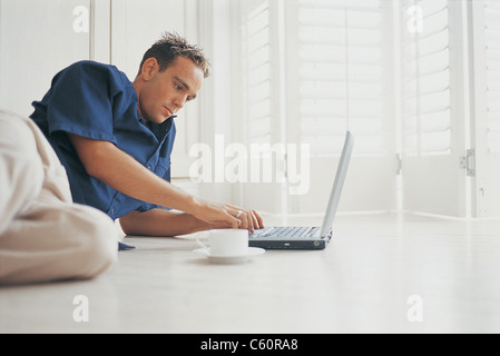 Man using laptop on floor Stock Photo