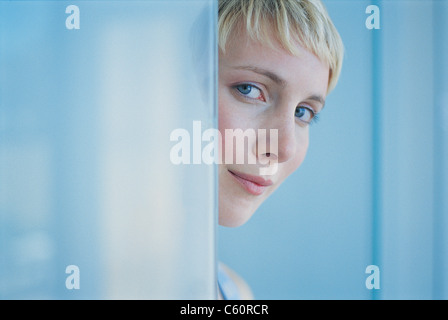Woman peeking around doorway Stock Photo