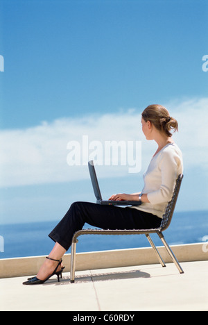 Businesswoman using laptop on roof Stock Photo