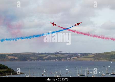 Two Red Arrows jets crossing over in an air display above Falmouth, Cornwall UK Stock Photo