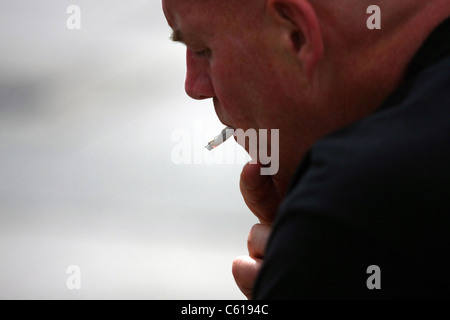 a The head of a man smoking a half smoked cigarette Stock Photo