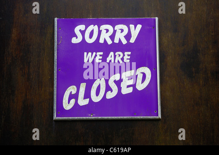 Sorry we are closed sign pinned to a wooden door. Stock Photo