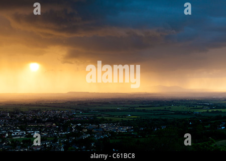 The view from Cleeve Hill - A rain storm at dusk approaching Bishops Cleeve, Gloucestershire -  Malvern Hills in the background. Stock Photo