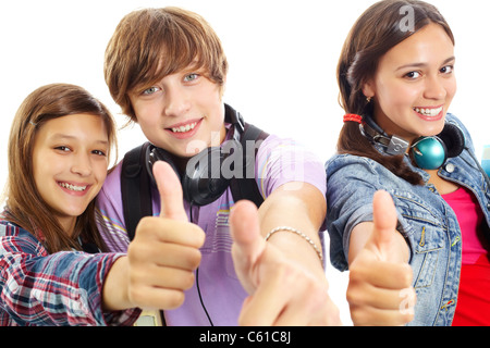 Cute teens with headphones showing thumbs up and smiling at camera Stock Photo