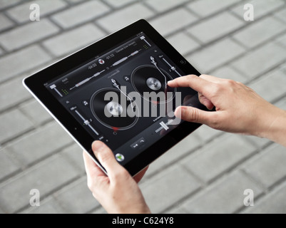 A woman outdoors mixing music in Djay Algoriddim on Apple Ipad2 Stock Photo