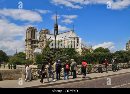 Notre Dame Cathedral, Paris, France. Tourists examine the 'love locks' left on the fence of the Pont Des Arts. Stock Photo