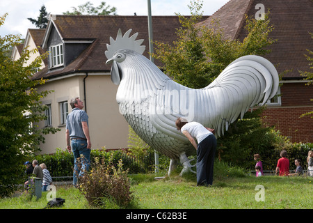 A couple inspect the giant Dorking cockerel that adorns the roundabout at the junction of the A24 and A25, in Dorking, Surrey Stock Photo