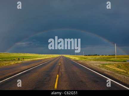 The prairies South Dakota SD the rainbow against stormy sky over a empty road pictures images photos large high resolution horizontal in USA US hi-res Stock Photo
